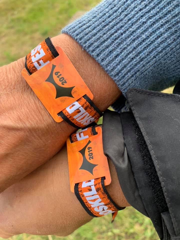 Billede af to arme med de orange adgangsarmbånd til Roskilde Festival