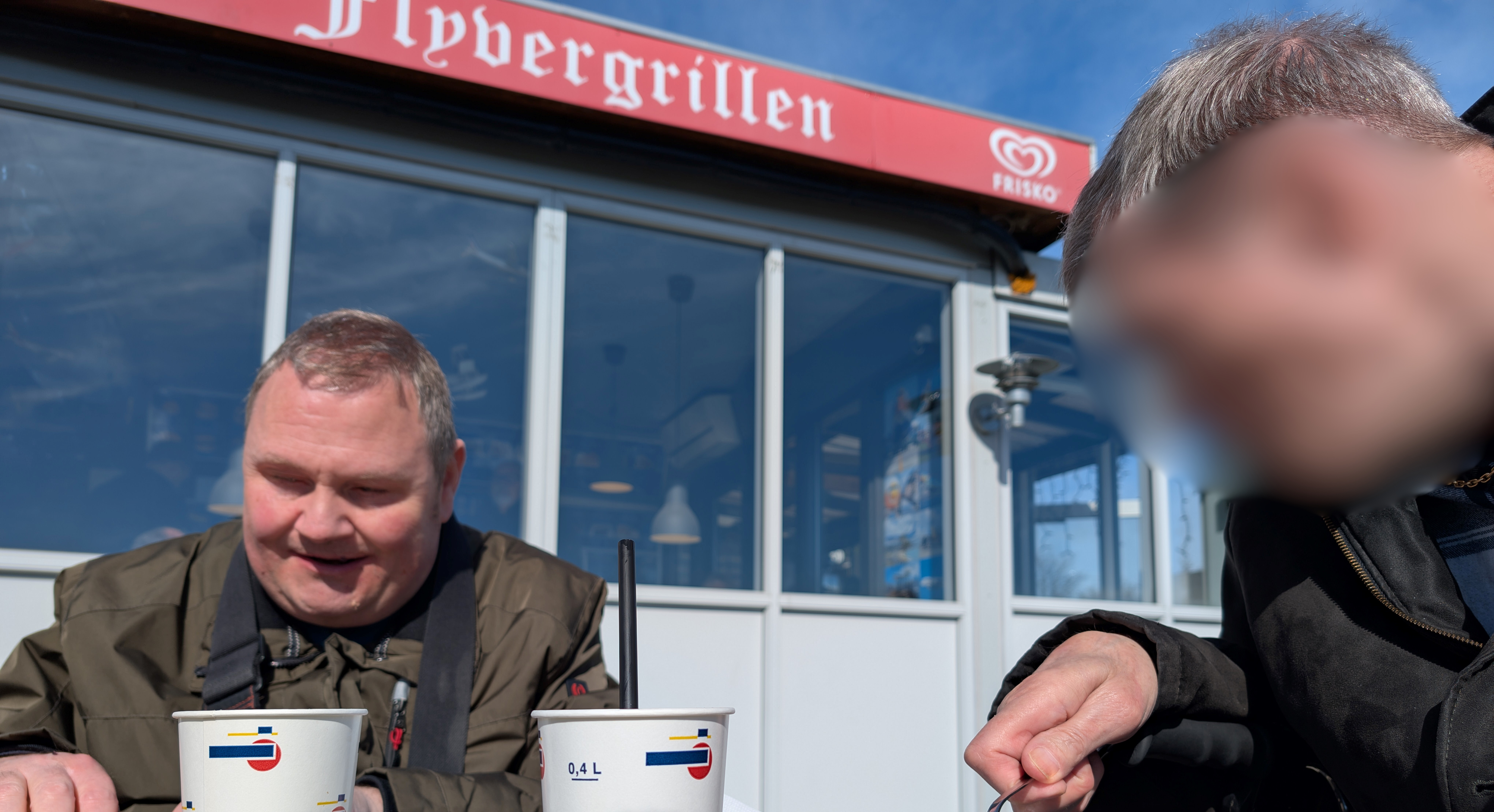 Mads og Preben i solskinnet ude foran Flyvergrillen med en kold sodavand.