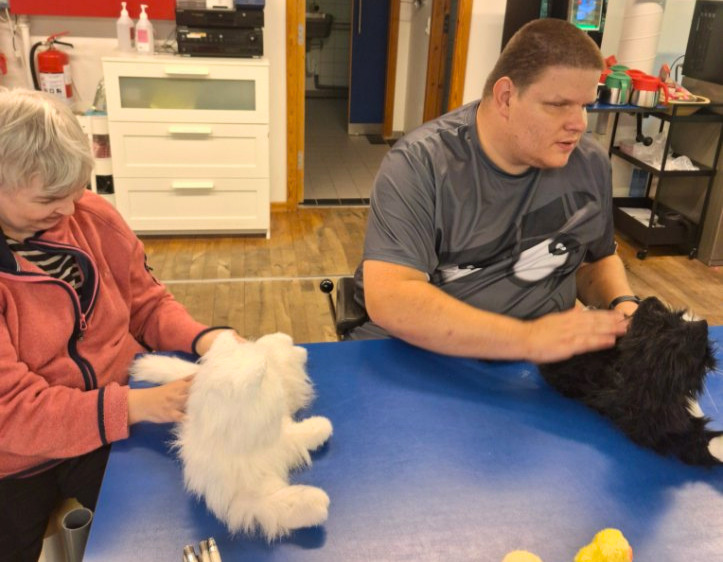 Kristina og Nicholas med hver sin robotkat. Kristina sidder med dagtilbuddets hvide robotkat Pjevs og Nicholas sidder med sin sorte Miv Miv. 