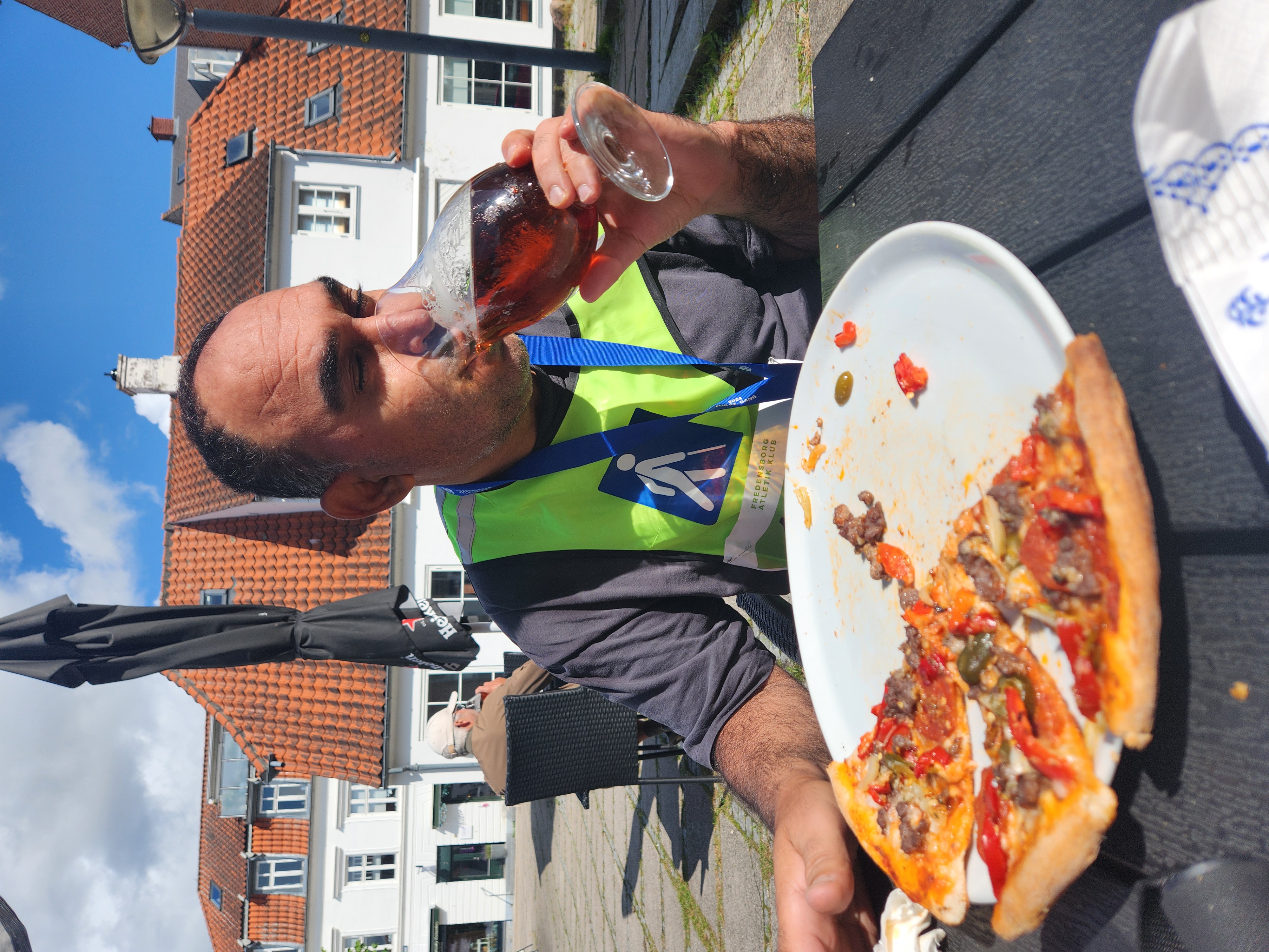 Yakup nyder en stor øl og en pizza efter løbet.