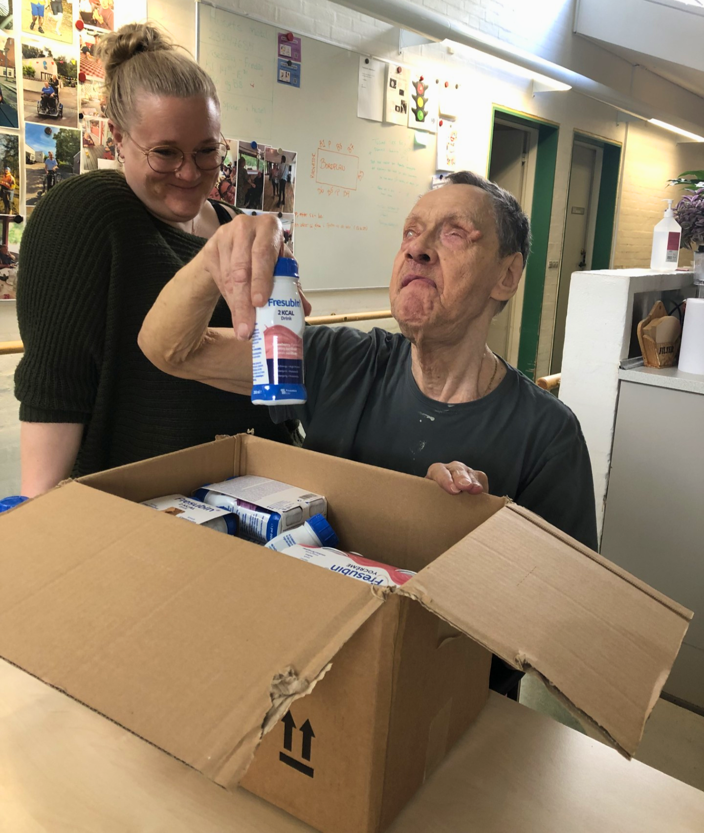 Mogens åbner papkasse med proteindrikke. 