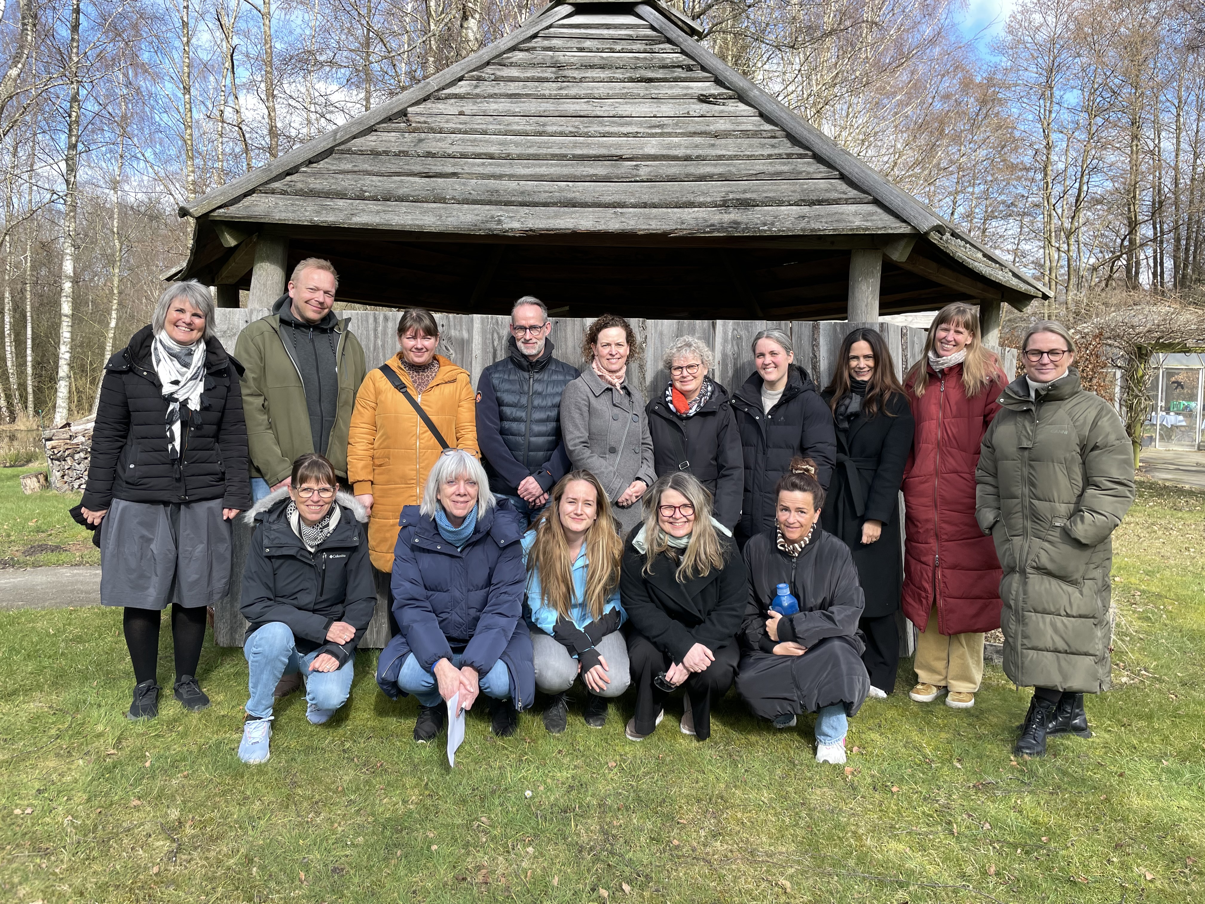 Gruppefoto af de studerende og tre af underviserne ved bålhytten i Bredegaards park. 