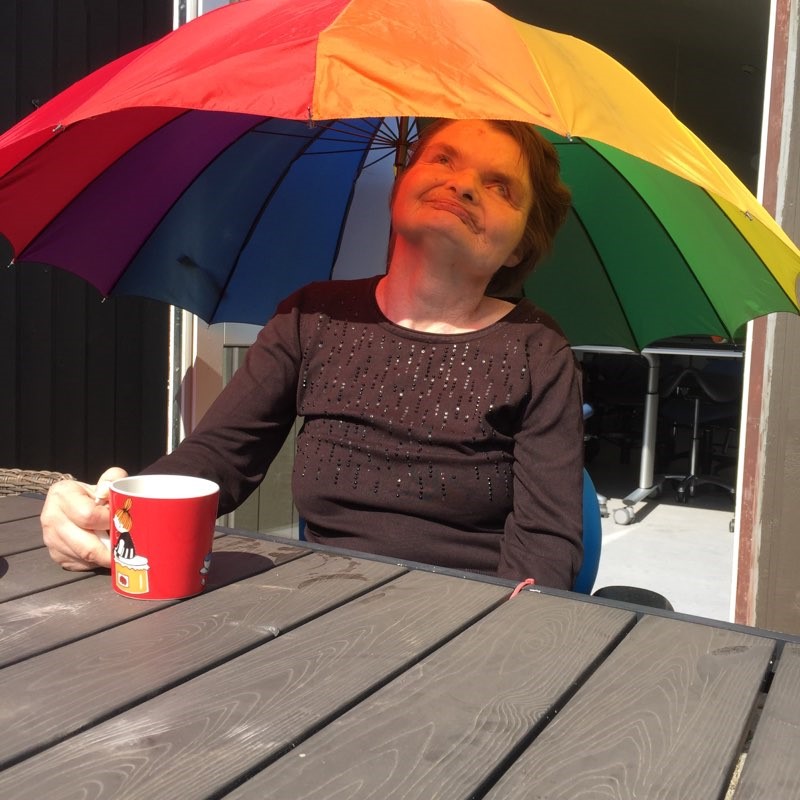 Lone drikker en kop kaffe under paraplyen.