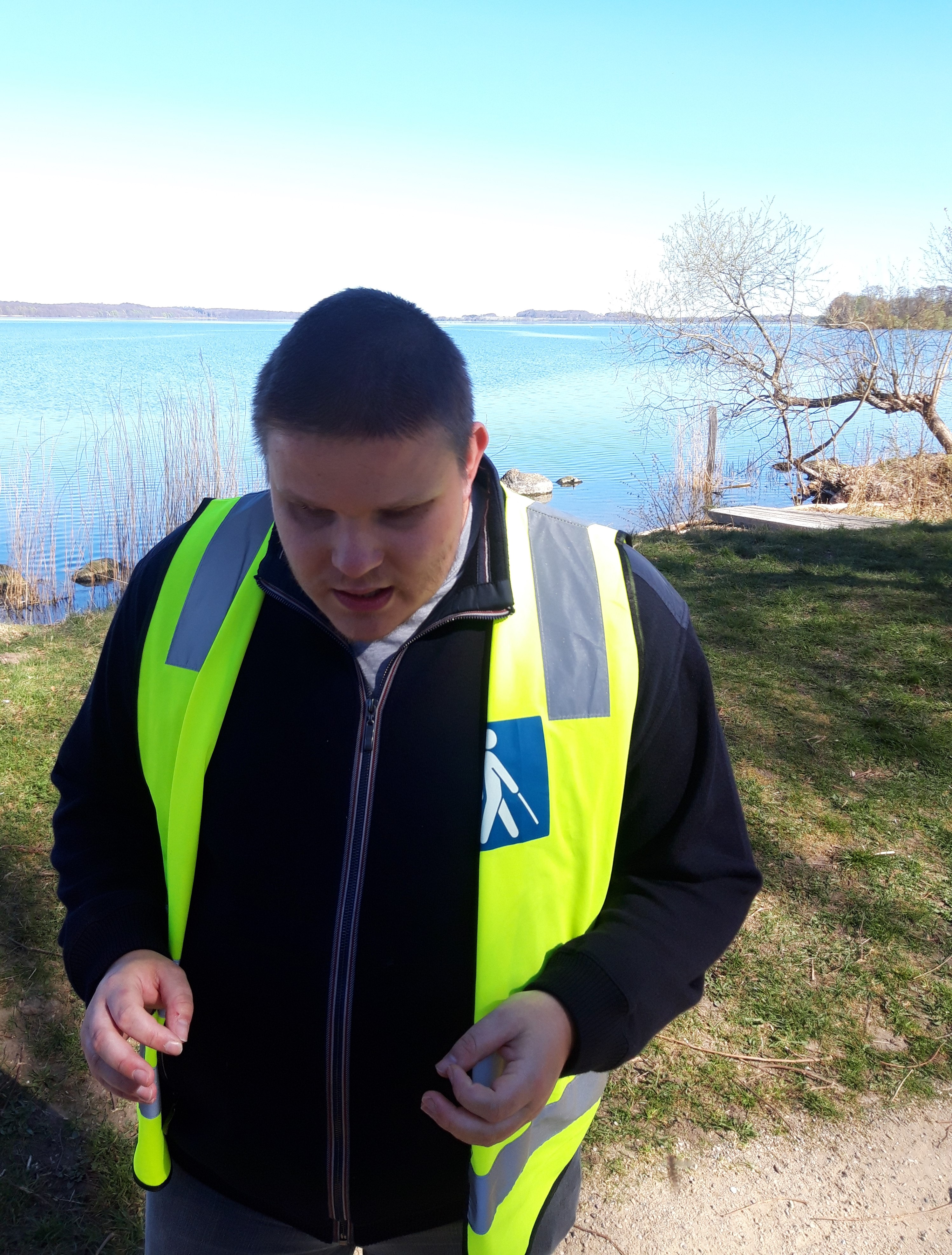 Nicholas på gåtur ved Esrum Sø. Den gule vest fortæller omgivelserne at Nicholas er blind.