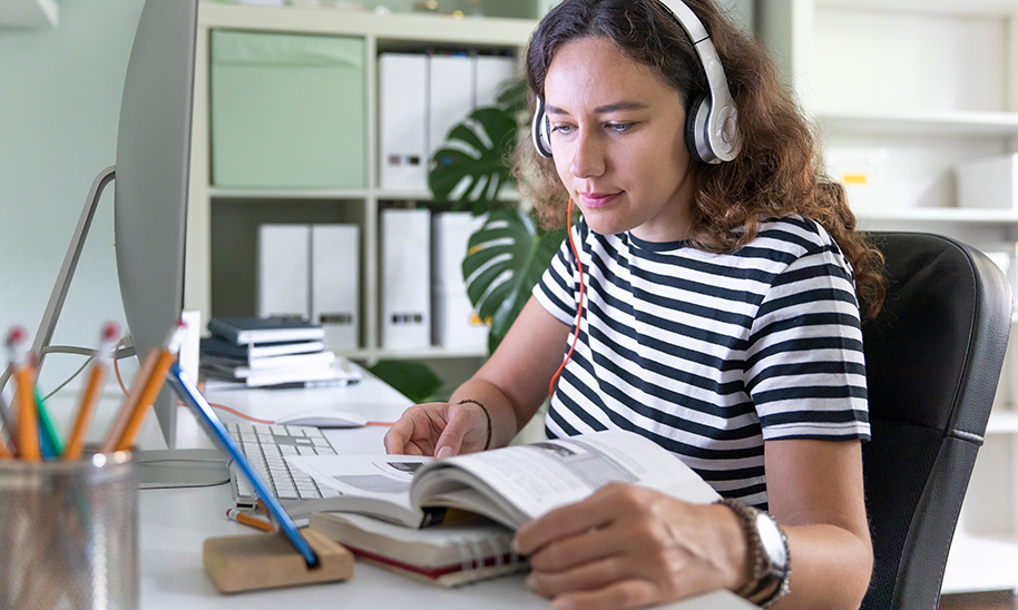 Ung kvinde ved pc med høretelefoner - Colourbox